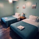 South Villa guest room at Mars Bay Bonefish Lodge with double beds, white linens, and a built-in vanity.