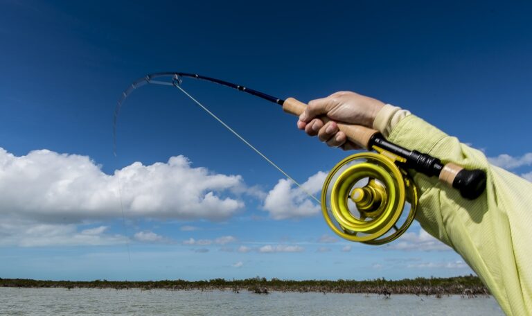 Angler holding a fast fly rod as fly line peels off the reel – fast fly rods explained