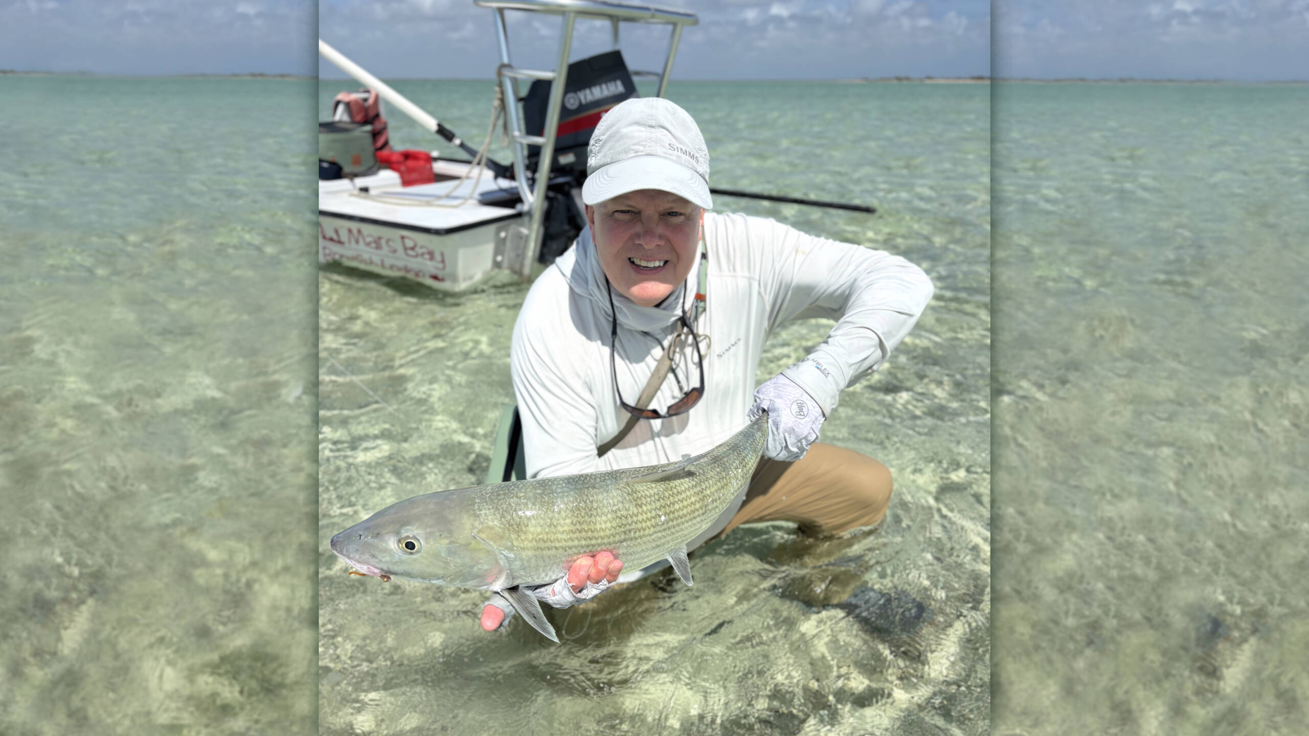 Angler holding a large bonefish in clear shallow water near Mars Bay Bonefish Lodge