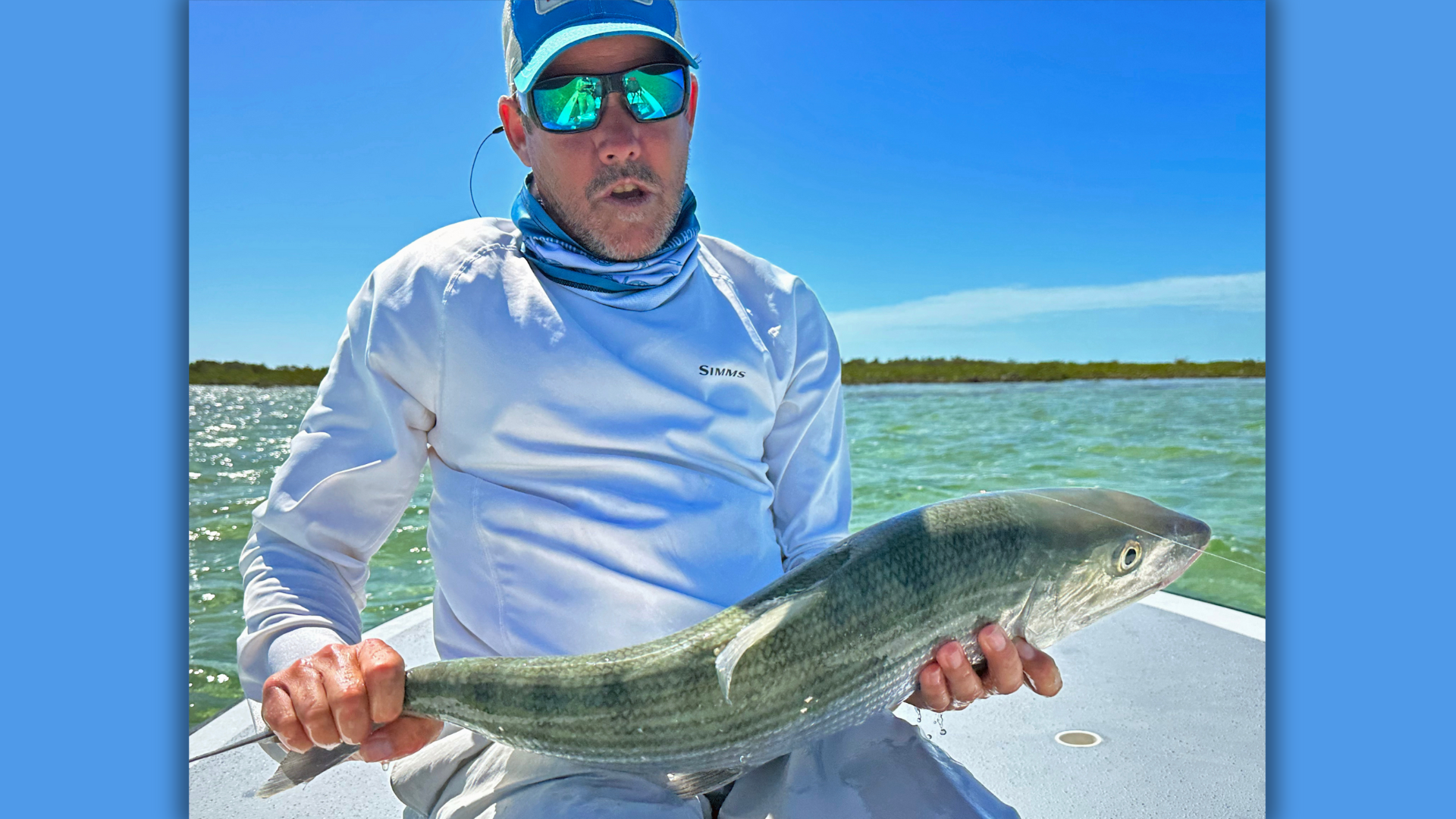 Angler holding a bonefish on the bow of a skiff near Mars Bay, Bahamas