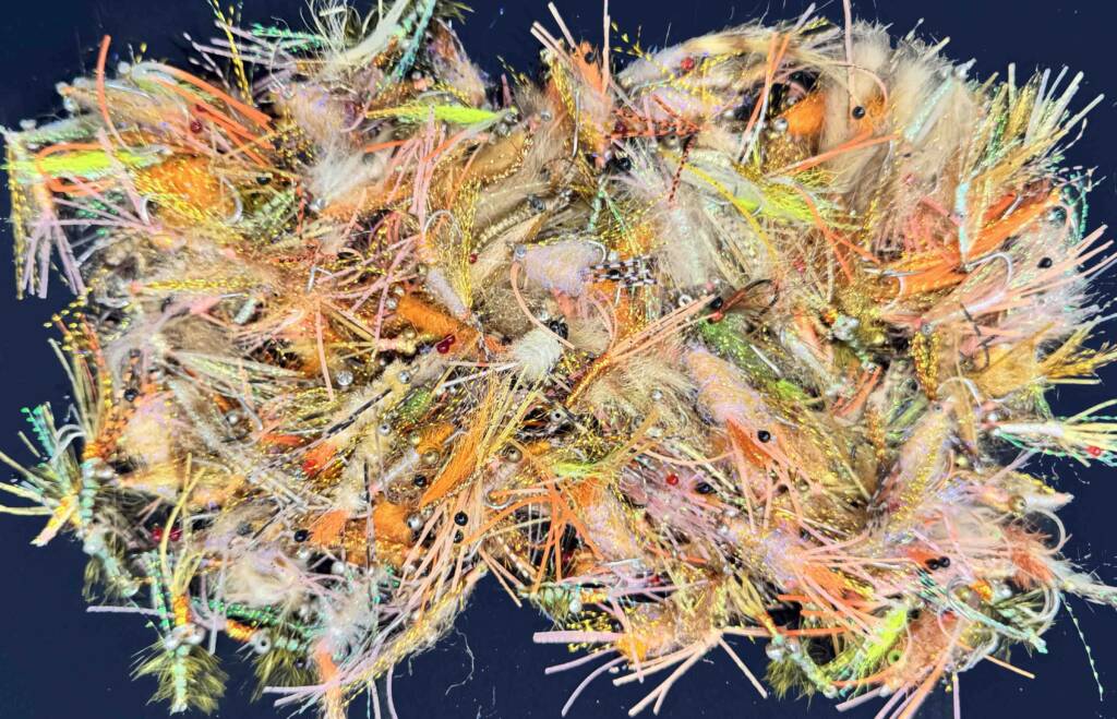 A large, tangled pile of bonefish flies in a mix of orange, tan, pink, and gold, tied by a returning angler without using recipes.